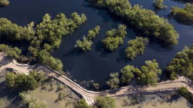 Earthen dams separate black water (top) from muddy water (bottom) at Inland Environmental & Remediation, Inc., south of Columbus, Texas, on April 14, 2019.